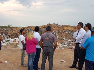 Promotor de Justiça com várias pessoas, diante de um lixão