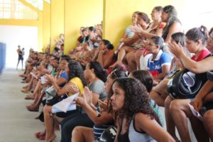 Pessoas sentadas em quadra poliesportiva