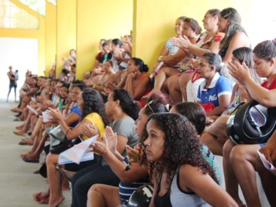 Pessoas sentadas em quadra poliesportiva