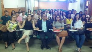 Pessoas sentadas em sala de aula e sorrindo para a pessoa que faz a fotografia delas
