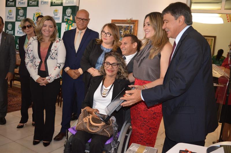 Pessoas de pé junto com pessoa cadeirante 