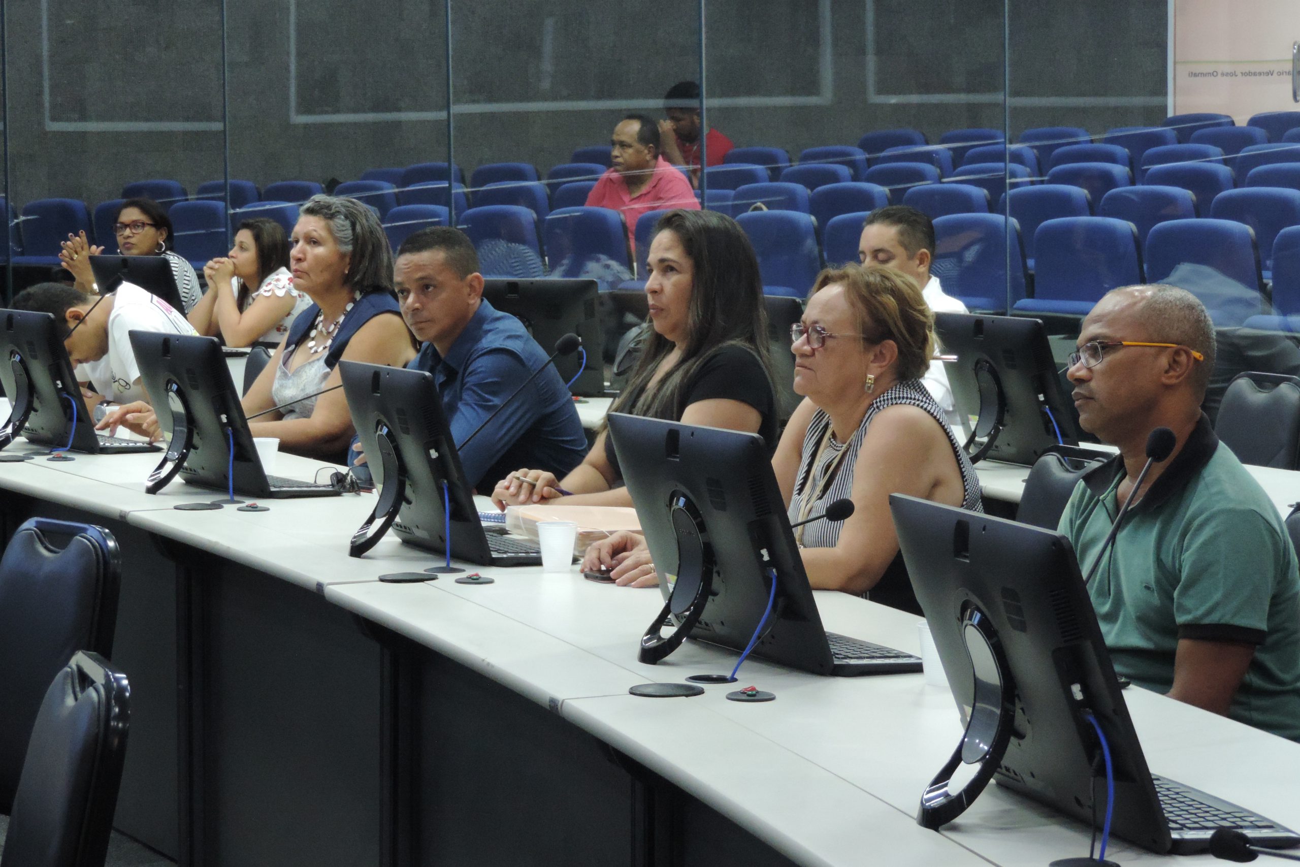 Pessoas sentadas atrás de uma mesa com computadores 