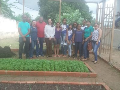 Promotora com alunos e professores em horta de escola