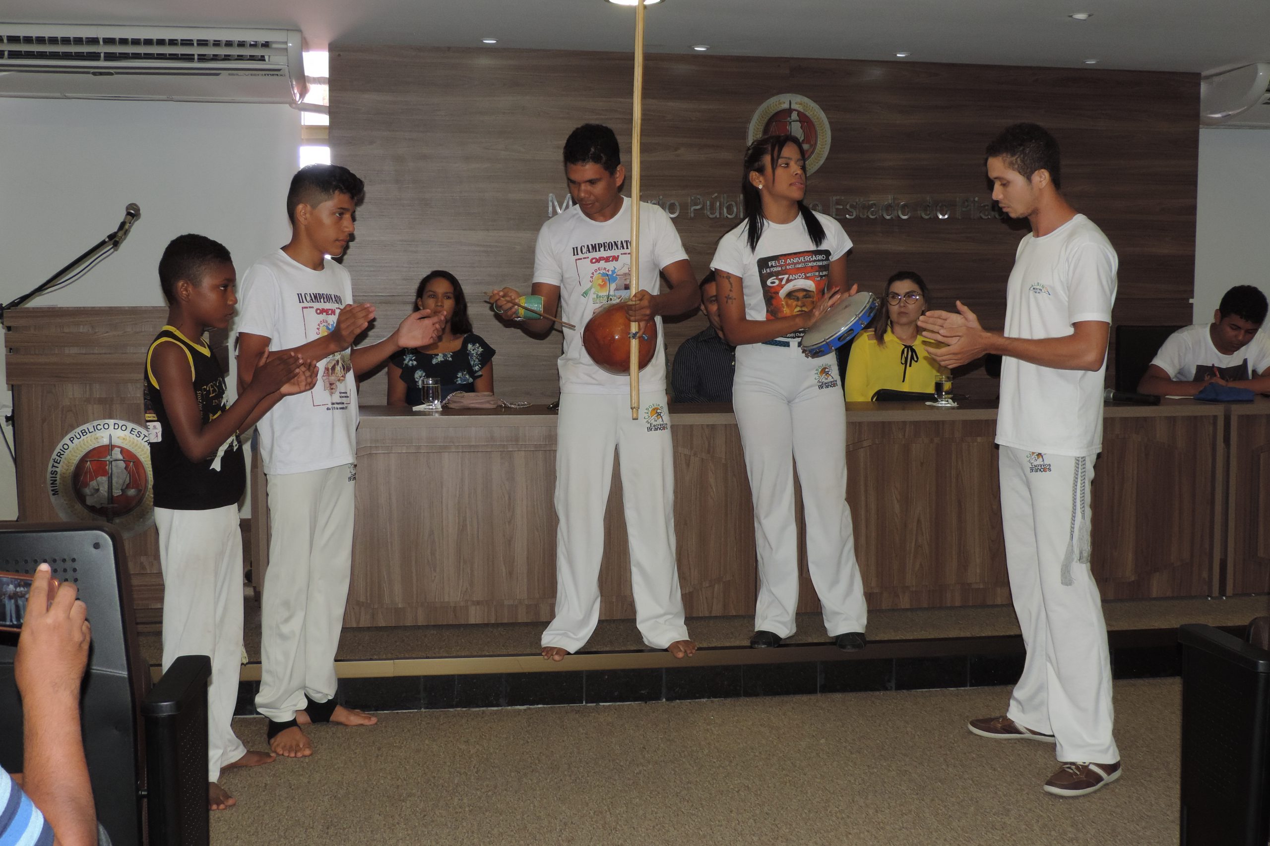 Pessoas de pé tocando capoeira 