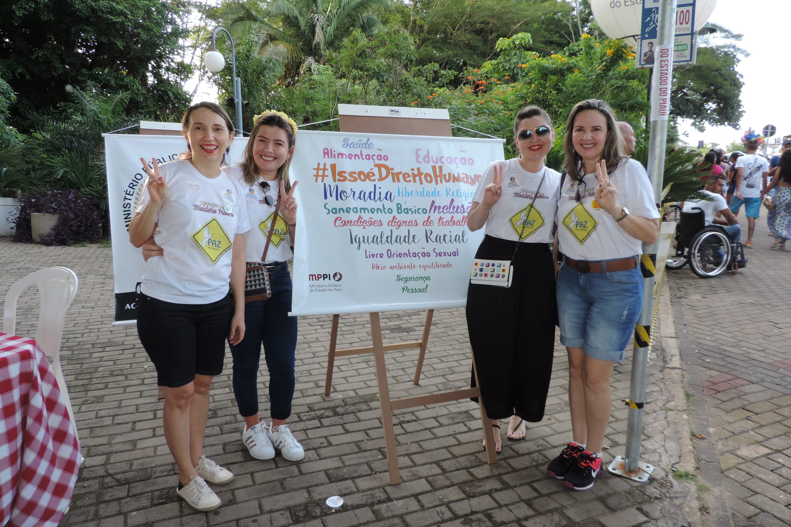 Pessoas de pé sorrindo ao lado de um cartaz 