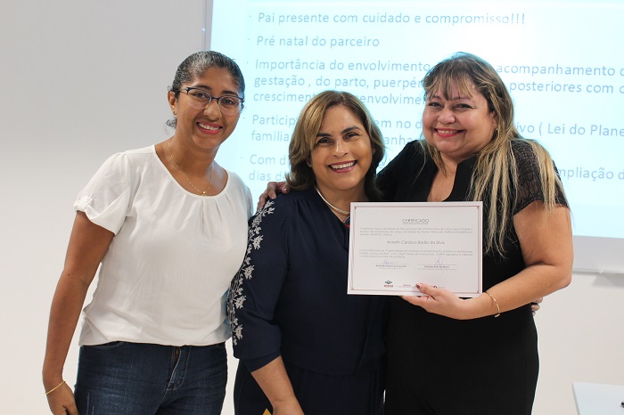 Três mulheres de pé sorrindo para fotografia 