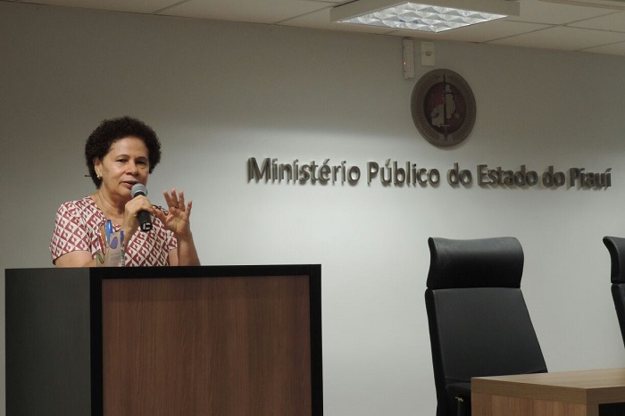 Mulher de pé falando com microfone nas mãos