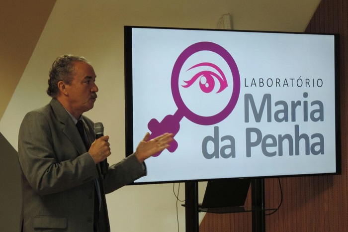 Homem de pé falando com microfone nas mãos