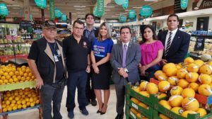 Pessoas em pé entre frutas e verduras de um supermercado