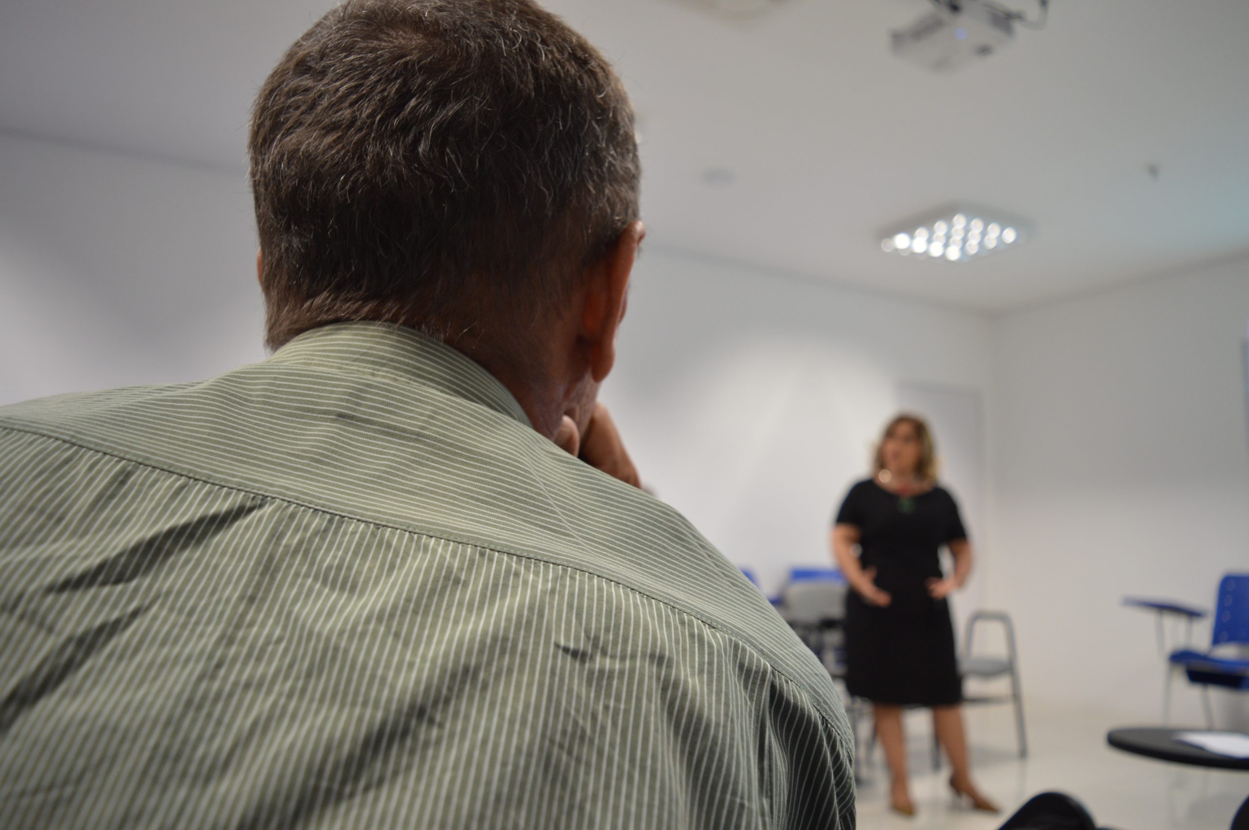 Pessoas sentada olhando uma mulher que está de pé falando 