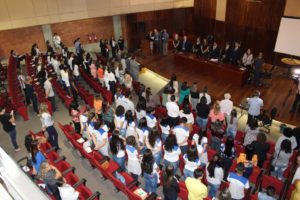 Pessoas de pé em auditório durante abertura de evento