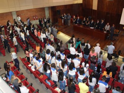 Pessoas de pé em auditório durante abertura de evento