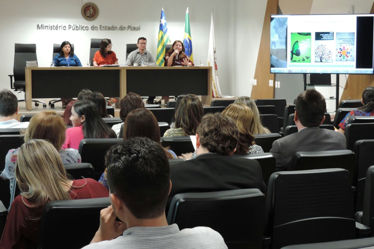 Pessoas sentadas em auditório olhando para outras pessoas que estão sentadas a sua frente 