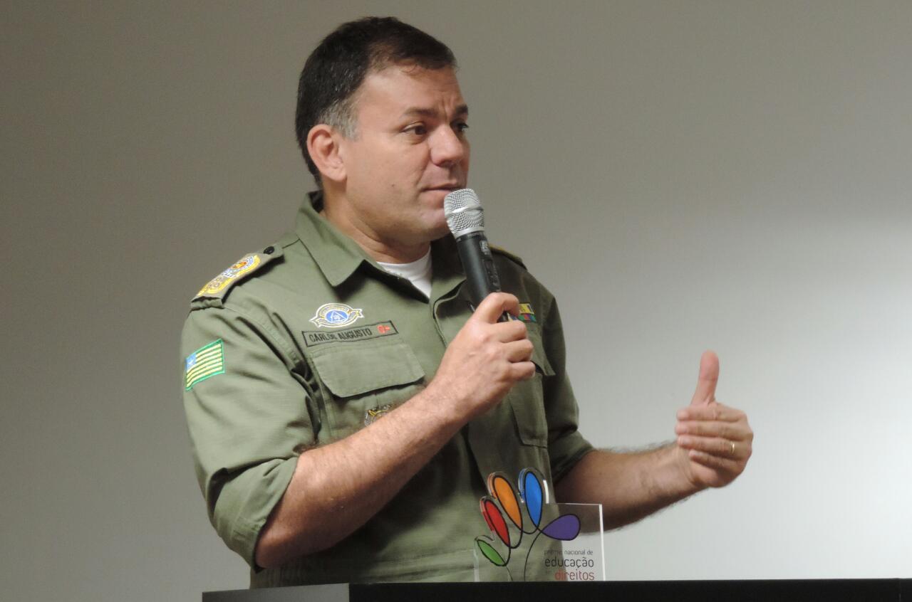 Homeme de pé falando com microfone nas mãos