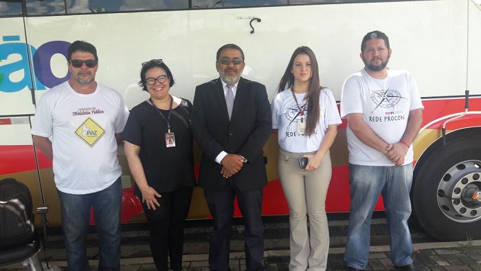 Pessoas de pé sorrindo na frente do ônibus do PROCON Itinerante 
