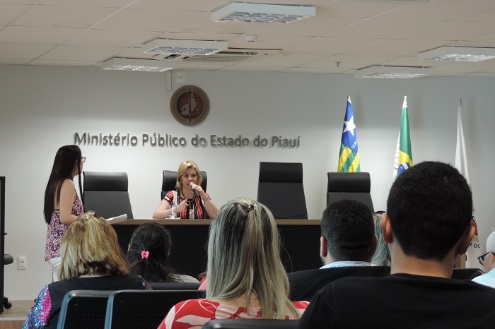Pessoas sentadas observando uma mulher ao fundo