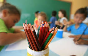 IMAGEM ILUSTRATIVA Foto que mostra, em primeiro plano, vários lápis coloridos. Ao fundo, crianças desenham na escola.