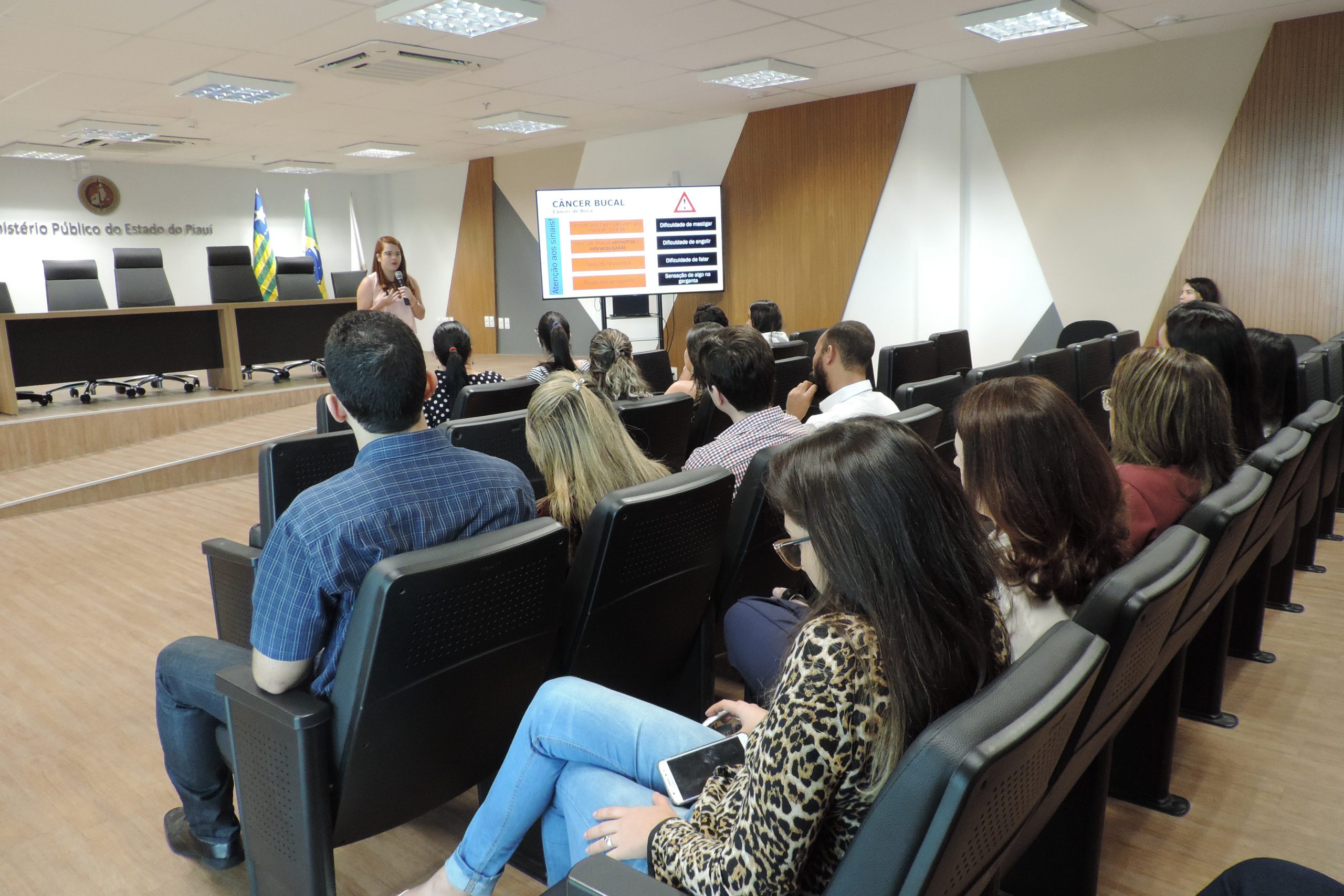 Pessoas sentadas em auditório assistindo palestra 