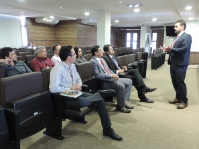 Pessoas sentadas em auditório assistindo apresentação