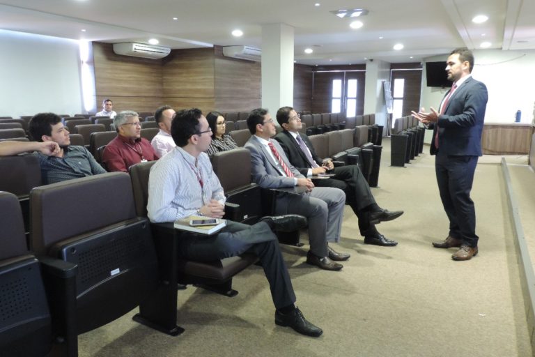Pessoas sentadas em auditório assistindo apresentação