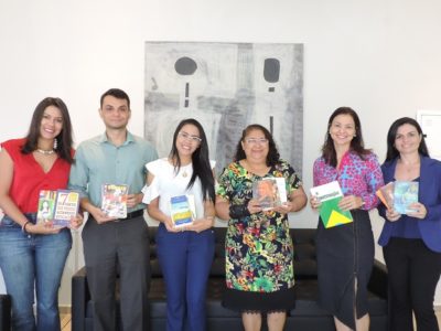 Pessoas de pé sorrindo e segurando livros nas mãos
