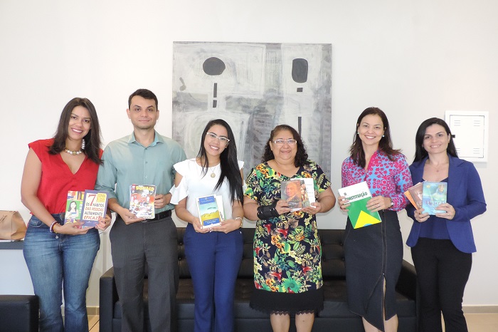 Pessoas de pé sorrindo e segurando livros nas mãos
