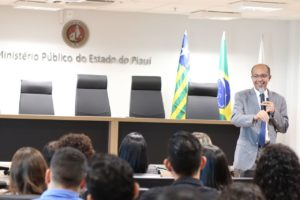 Homem de pé falando com o público sentado que o observa