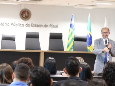 Homem de pé falando com o público sentado que o observa