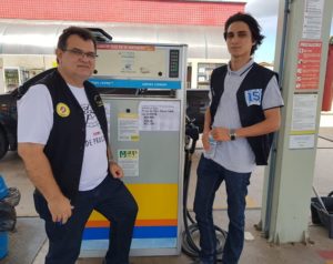 Duas pessoas de pé olhando para um bomba de combustível