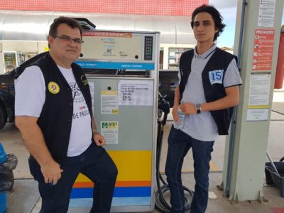 Duas pessoas de pé olhando para um bomba de combustível