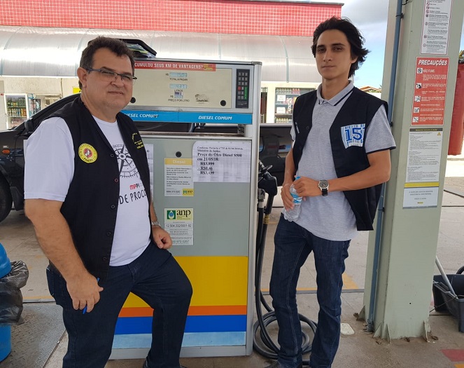 Duas pessoas de pé olhando para um bomba de combustível