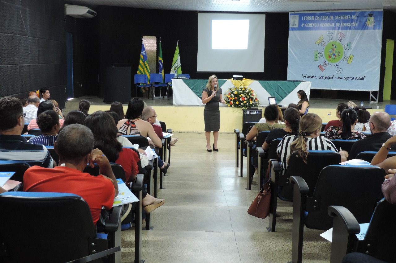 mulher de pé falando com microfone nas mãos 