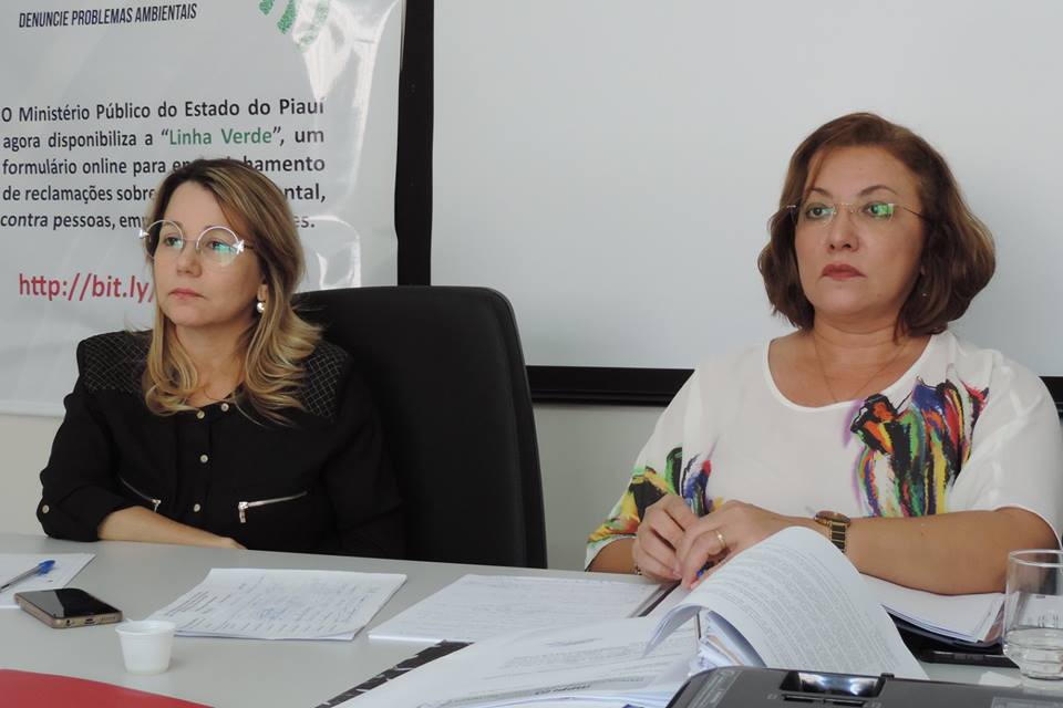 Duas mulheres sentadas olhando para as pessoas que estão à sua frente 