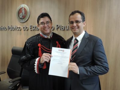 Duas pessoas de pé segurando um papel