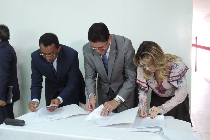 Pessoas assinado um documento que está sobre uma mesa 
