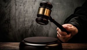 Mão de pessoa segurando um martelo de tribunal.