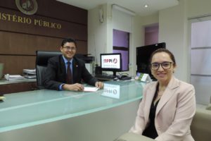 Homem assinando documento enquanto mulher posa para a fotografia.a