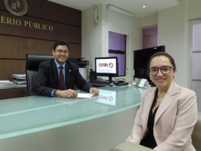 Homem assinando documento enquanto mulher posa para a fotografia.a