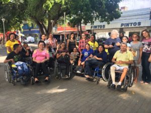 Pessoas de pé atrás de cadeirantes sorrindo para fotografia