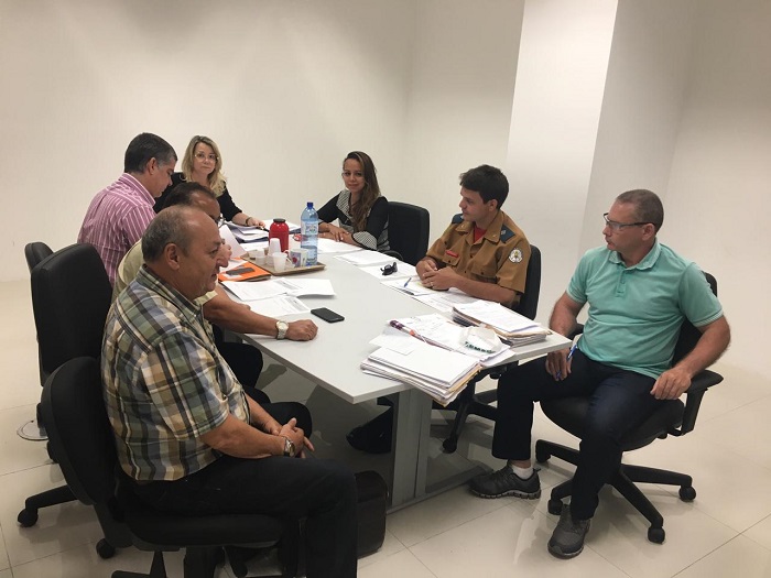 Pessoas sentadas em volta de uma mesa conversando durante reunião que resultou na assinatura de Termos de Ajustamento de Conduta 