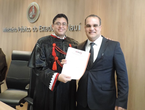 Duas pessoas de pé sorrindo e segurando um papel