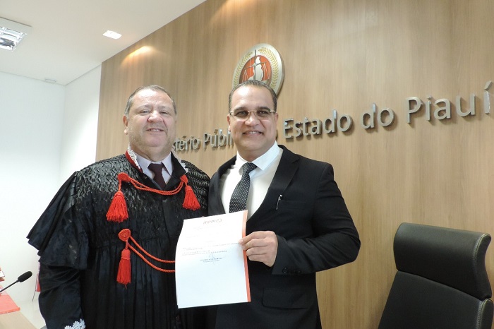 Duas pessoas de pé sorrindo e segurando um papel 