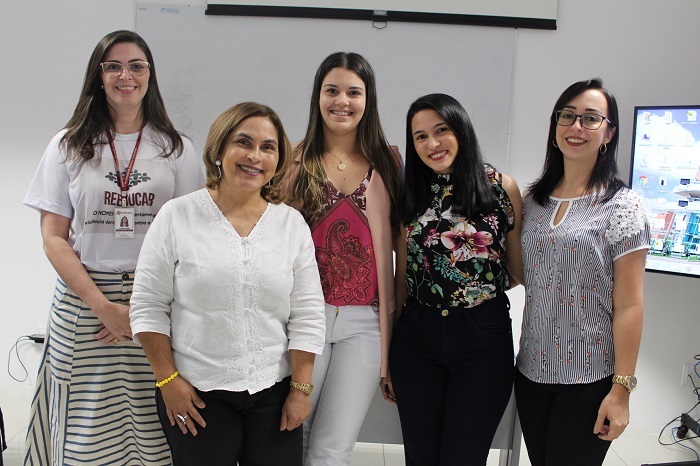 Foto de um grupo de mulheres de pé e sorrindo 
