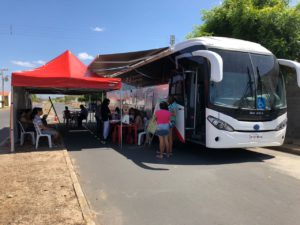 Pessoas debaixo de uma barraca do PROCON ao lado do ônibus que atendeu a população do Residencial Eduardo Costa