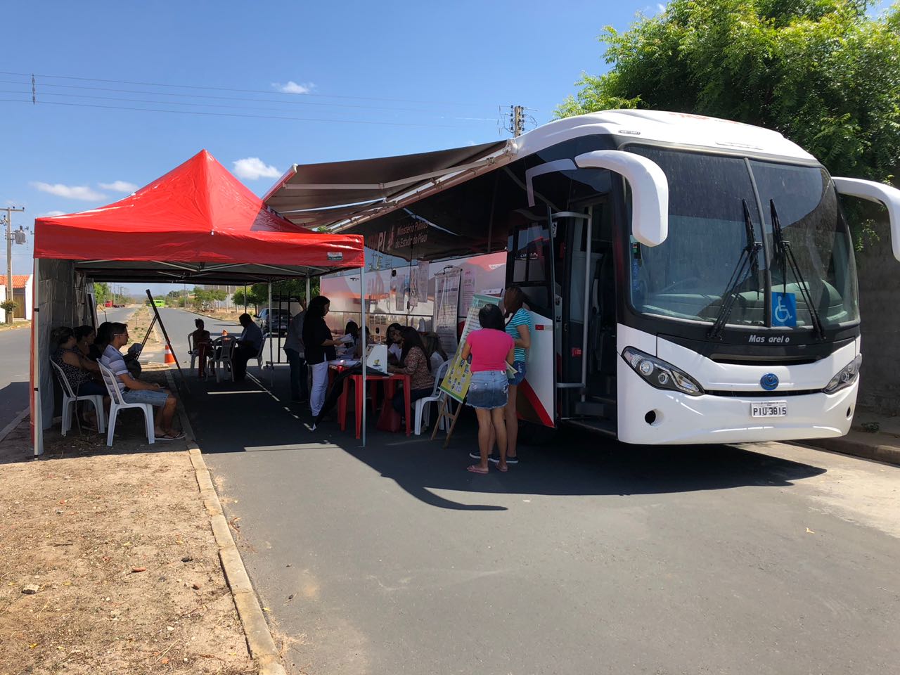Pessoas debaixo de uma barraca do PROCON ao lado do ônibus que atendeu a população do Residencial Eduardo Costa