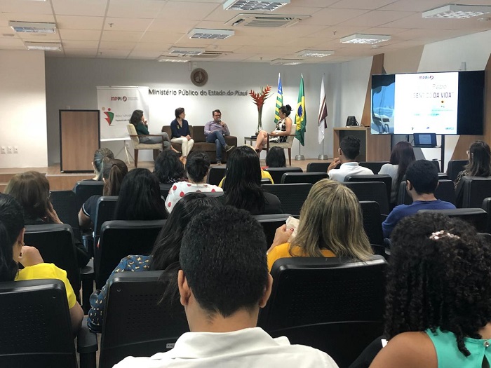 Pessoas sentadas em auditório assistindo palestras 
