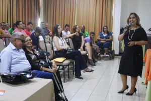 A promotora de Justiça Amparo paz de pé em frente uma plateia que a assiste durante palestra