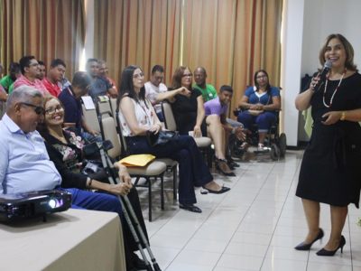 A promotora de Justiça Amparo paz de pé em frente uma plateia que a assiste durante palestra