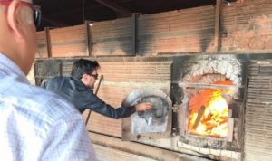 Pessoas com pacote de produtos entorpecentes nas mãos e jogando esse pacote dentro de um forno