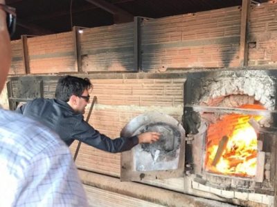 Pessoas com pacote de produtos entorpecentes nas mãos e jogando esse pacote dentro de um forno